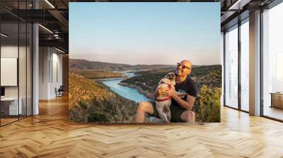 Happy young man in the field with his pug breed dog. Portrait of boy with his dog in the mountain Wall mural