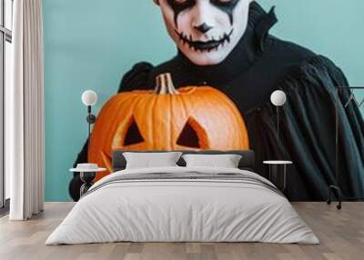 A man in a black costume holding a pumpkin with a smile on it Wall mural