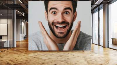 A man with a big smile on his face is making a gesture of excitement. He is wearing a gray shirt and has a beard Wall mural