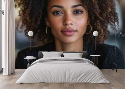 A woman with curly hair is sitting at a table with a laptop. She has a serious expression on her face Wall mural