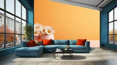 Bouquet of beautiful chamomiles in vase on table against orange background. Wall mural