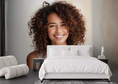 Portrait of beautiful young woman with curly hair smiling at camera. Wall mural