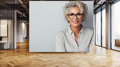 Portrait of happy older businesswoman in eyeglasses smiling at camera. Wall mural