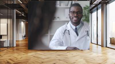 Male doctor with African-hair listening to female patient at hospital exam, health Wall mural