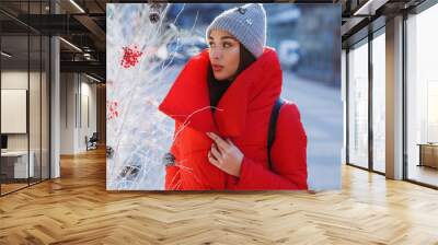 Beautiful woman in red winter jacket walks along the street covered with snow in a beautiful old European city. Christmas, new year and winter holiday concept - Image Wall mural