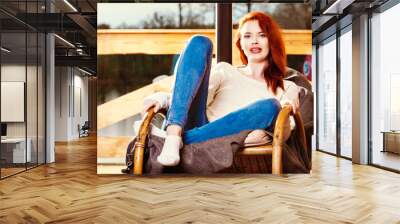 Atractive red-haired woman resting sitting on Rocking chair in f Wall mural