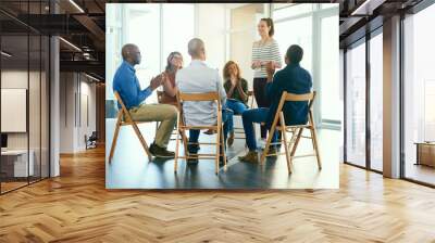 Business woman coaching a teamwork seminar at work about job motivation and success. Group of office workers clapping hands after a team presentation. Smiling colleagues sitting together in a meeting Wall mural