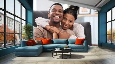 Love, hug and portrait of a happy couple on sofa in the living room of their modern home. Happiness, smile and black woman relax with husband, care and marriage on couch at the house lounge together Wall mural