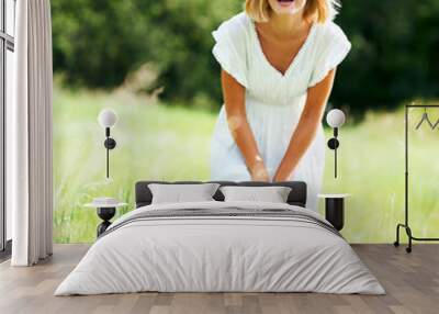 Nothing beats a good laugh. Cute young woman laughing while standing in a field outdoors. Wall mural