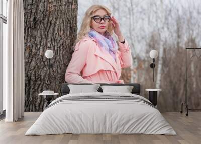 Woman in pink coat jacket , lilac scarf, cat eye glasses, portrait of blonde nice lady, trendy concept Wall mural