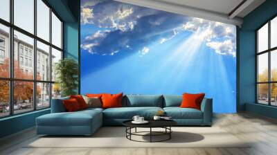 Sun light rays or beams bursting from the clouds on a blue sky. Spiritual religious background. Wall mural