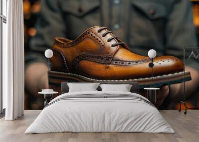 Artisan cobbler's hand holds brown leather shoe for restoration work in dimly lit repair shop. Wall mural