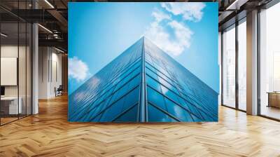 A tall building with a modern style and reflective glass windows, under a clear blue sky Wall mural