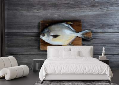 Overhead view of a fresh whole silver pomfret fish on wooden serving board Wall mural