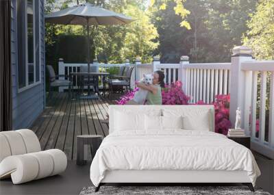 Woman hugging her dog while outdoors on home deck Wall mural