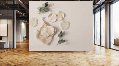 Bio organic cotton reusable round pads for make up removal. Dry eucalyptus branches.and knitted bag. Beige table background. Zero waste concept. Sustainable bathroom and lifestyle. Flat lay, top view. Wall mural