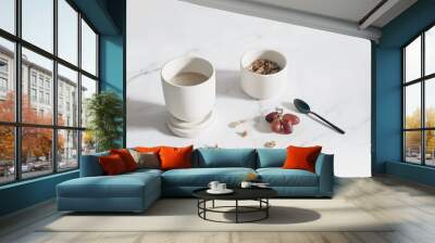 Breakfast, snack still life scene. Cup of coffee, red grapes fruit on white marble table in sunlight. Bowl with muesli, granola and oat cereals and black spoon. Healthy eating, diet concept. Top view. Wall mural