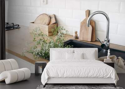 Closeup of kitchen interior. White brick wall, metro tiles, wooden countertops with chopping boards. Cow parsley plants in black sink. Modern scandinavian design. Home staging, cleaning concept. Wall mural