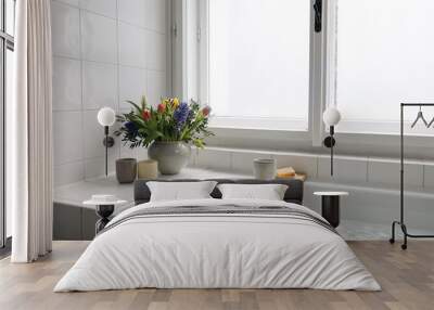 Home spa relaxation concept. Bathtube with cup of coffee, candles and book. Fresh spring bouquet. Wall mural