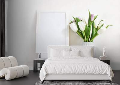 White blank wooden frame mockup with spring bouquet of tulips in porcelain vase and pile of books lying on the table. Poster product design. Styled stock feminine photography. Home decor. Wall mural