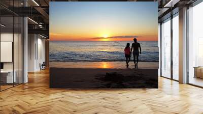 A man and his daughter walking on the beach during sunset Wall mural