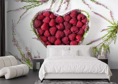 Raspberry berries in a heart shape bowl and heather flowers Wall mural