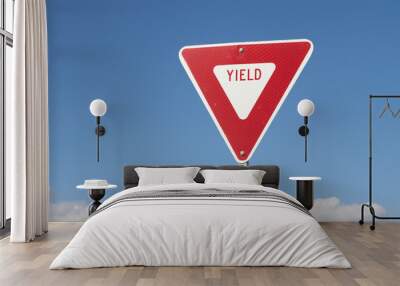 YIELD sign isolated against a blue sky background. A yield or give way sign indicates that merging drivers must prepare to stop if necessary to let a driver on another approach proceed. Wall mural