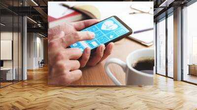 Online healthcare app on smartphone screen. Closeup of male hands touching smartphone screen at table. Wall mural