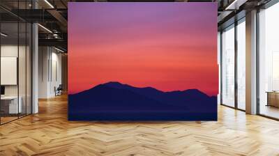 Beautiful colorful sunset seen from the island surrounded with sea over the high mainland hills  Wall mural