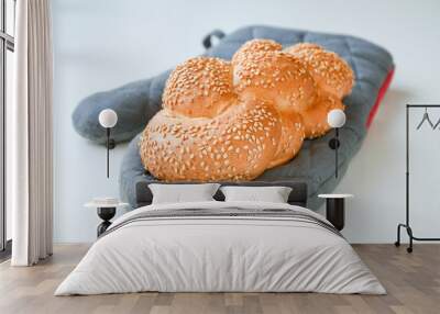 Freshly baked brown sesame braid on a grey baking glove Wall mural