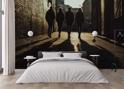 Silhouettes of four young adults walking together in an urban alleyway at dusk. Wall mural