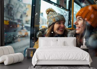 Two smiling women in winter attire share a moment on a bus during a snowy day. Wall mural