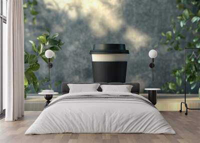 Black coffee cup with lid surrounded by greenery in natural light on a wooden surface Wall mural