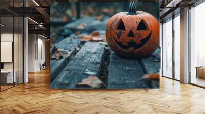 A carved Halloween pumpkin resting on a weathered wooden table surrounded by autumn leaves Wall mural