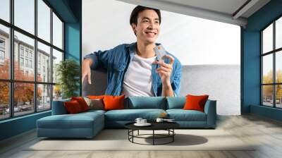 A young handsome Asian man smiles freely and is confident holding a credit card in his hand he is ready to shop things. An Internet wireless Online technology and online shopping concept idea Wall mural