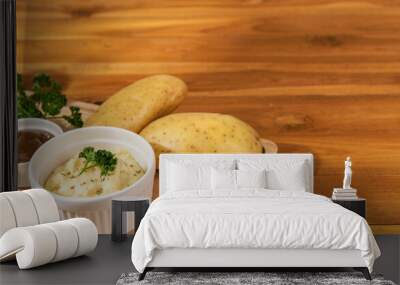 Close up mashed potato dish menu with brown gravy in wooden tray with potatoes, parsley on wooden table warm light background. Copy space text banner. Eatable international food recipe concept ideas Wall mural