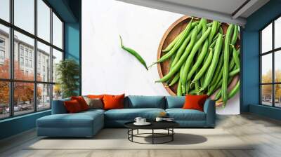 Green beans in a wooden plate on a white background, top view Wall mural