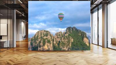 Colorful hot air balloon is flying over the mountain and jungle at sunrise Wall mural