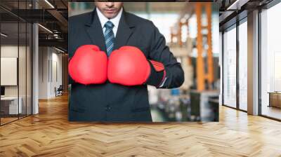 factory, training, aggression, industrial, exercising, masculine, muscle, competitive, fist, power. A man in a suit is holding two red boxing gloves. Concept of strength and determination. Wall mural