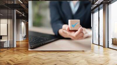 support, tick, voting, mark, decision, goal, improvement, plan, solution, strategy. A woman is holding a wooden block with a blue check mark on it. Concept of accomplishment or approval. Wall mural