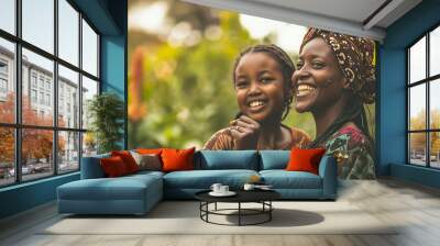 african mother and daughter smiling with raised fists in a lush garden. concept of black empowerment Wall mural