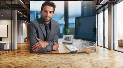 Driven to succeed. Portrait of a young businessman sitting at his desk. Wall mural