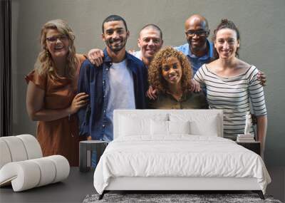 Friends all grouped together. Shot of a group cheerful friends standing together for a portrait while looking at the camera. Wall mural