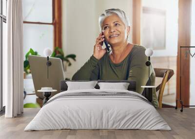 Her broker just called with some more good news. Shot of a mature woman talking on a cellphone while working on a laptop at home. Wall mural