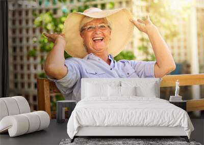 Portrait, laugh and senior woman with hat on bench, relaxation and glasses in garden. Joke, seat and elderly female person in backyard for happiness, comedy and funny with retirement in Canada Wall mural