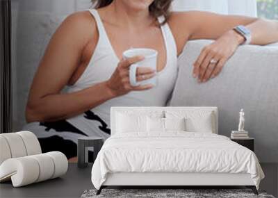 beautiful Hispanic woman sitting on a sofa with a coffee cup  Wall mural