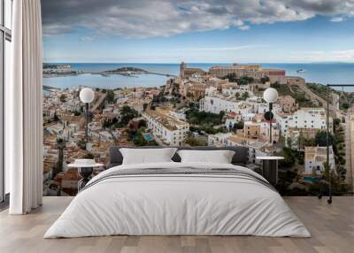 Aerial panorama of Ibiza town with fortifications, bastions, walls, churches, white houses against blue stormy cloudy sky Wall mural