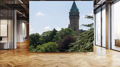 Clock tower in Luxembourg city centre behind green trees. Blue sky background. Wall mural