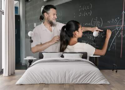 Maths lesson in a secondary school. Latin Female Teenager Student writing on Blackboard with help of friendly teacher in High School.  Wall mural