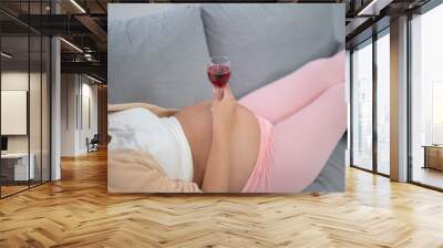 A portrait of happy Asian pregnant woman drinking wine alcohol beverage glass in bedroom at home. Having a baby. Family people lifestyle. Mom. Wall mural